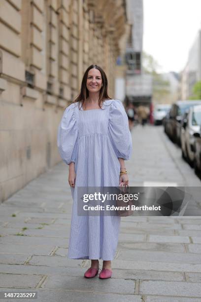 Alba Garavito Torre wears gold and green embossed pattern earrings, a baby blue and white striped print pattern puffy short sleeves / long dress from...