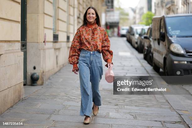 Alba Garavito Torre wears gold and black embossed pattern earrings, a camel with beige / blue / green / pink flower print pattern high neck / puffy...