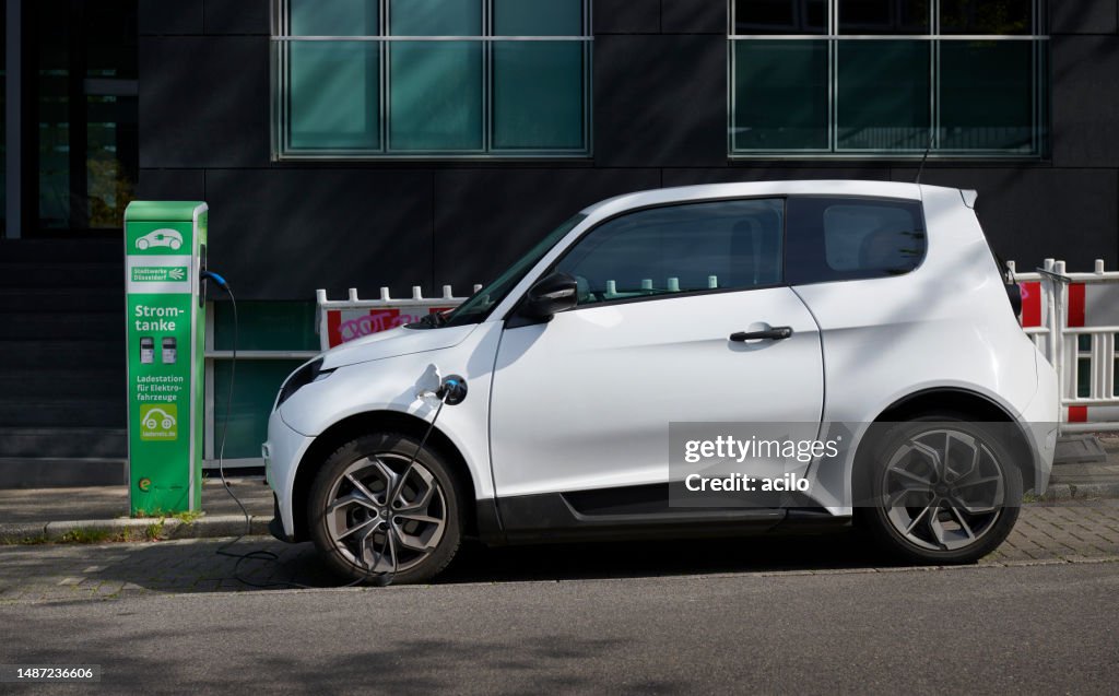 Small electric car / a white e.Go life and recharging station