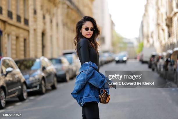 Patricia Gloria Contreras wears small black transparent sunglasses from Fendi, a gold large necklace, a black nylon high neck / long sleeves skinny...