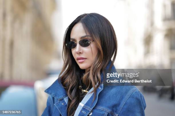 Patricia Gloria Contreras wears small black transparent sunglasses from Fendi, a gold large necklace, a black nylon high neck / long sleeves skinny...
