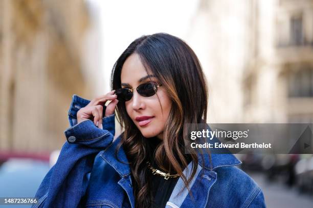 Patricia Gloria Contreras wears small black transparent sunglasses from Fendi, a gold large necklace, a black nylon high neck / long sleeves skinny...