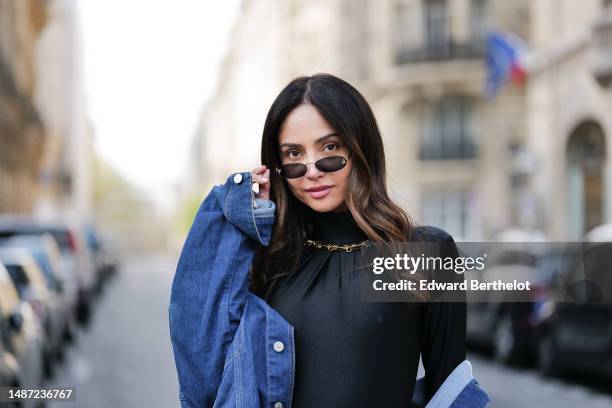 Patricia Gloria Contreras wears small black transparent sunglasses from Fendi, a gold large necklace, a black nylon high neck / long sleeves skinny...