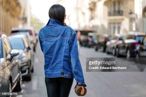 Patricia Gloria Contreras wears a black nylon high neck / long sleeves skinny jumpsuit from Daname, a navy blue denim jacket from Dior, a dark brown...