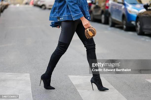 Patricia Gloria Contreras wears a black nylon high neck / long sleeves skinny jumpsuit from Daname, a navy blue denim jacket from Dior, a dark brown...