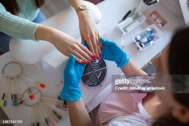 nail salon worker examining her customers nails - nail salon stock pictures, royalty-free photos & images