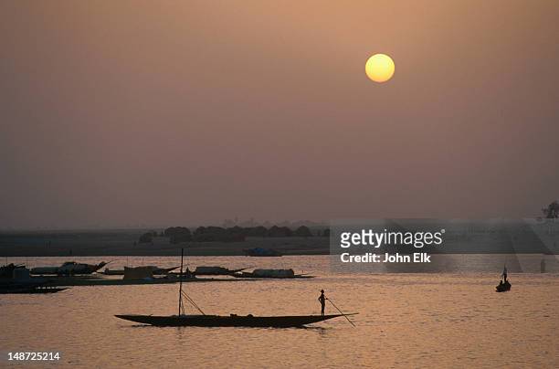a pirogue (dugout canoe) on the niger river at sunset with the mopti harbour in the background. - niger river stock pictures, royalty-free photos & images