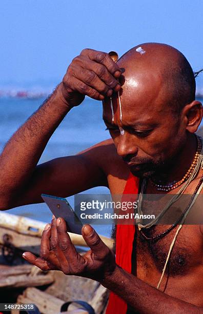 pilgrim applies tilak (forehead mark worn by devout hindu men) after bathing at the maha khumb mela (great urn festival) - tilaka stock pictures, royalty-free photos & images