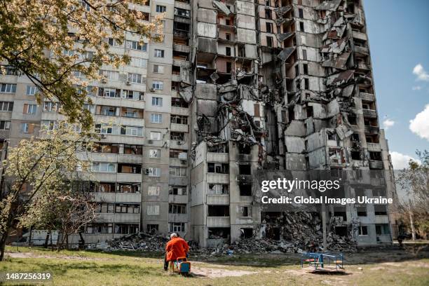 Man sits on a seesaw in front of a ruined residential building in Northern Saltivka, the district of the city most destroyed by Russian shelling, on...