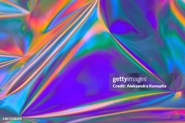 abstract vibrant purple, blue, mint green, orange, red metallic psychedelic holographic wrinkled foil texture. bold bright neon colored crazy new wave groovy style background - iridiscente fotografías e imágenes de stock