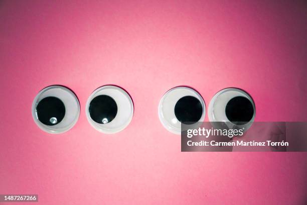 googly eyes on pink background. anger in the couple concept. - miope and humor fotografías e imágenes de stock