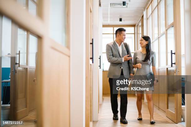 uomo d'affari cinese asiatico e donna d'affari che cammina nel corridoio. - chief administration office foto e immagini stock