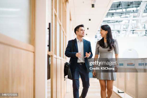 uomo d'affari vietnamita asiatico e donna d'affari cinese che camminano nel corridoio. - chief administration office foto e immagini stock