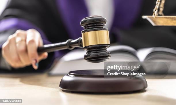 the female judge is taking a final sentence after reading documents and is aboutto hit a gavel on wood. - courthouse foto e immagini stock