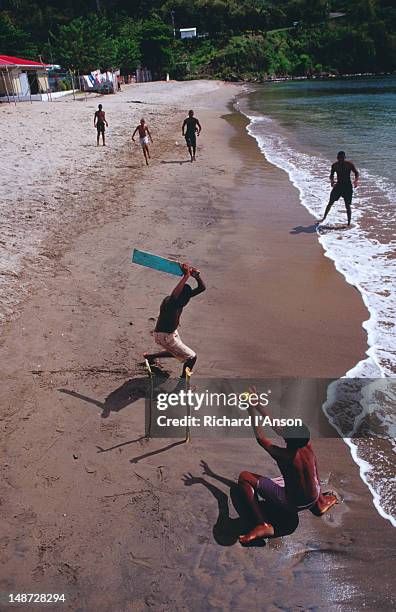 boys playing cricket on anse la raye beach. - beach cricket stock pictures, royalty-free photos & images