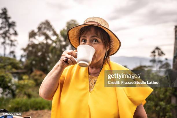 mujer madura bebiendo café en un campo agrícola - colombiano fotografías e imágenes de stock