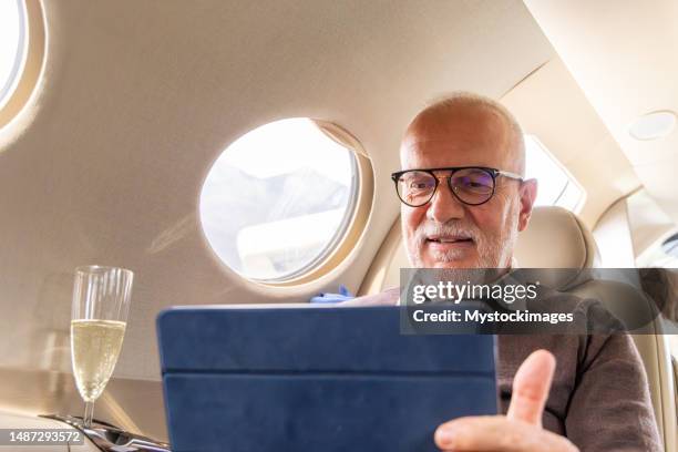 hombre de negocios senior trabajando en tableta digital en un jet privado - aircraft wifi fotografías e imágenes de stock