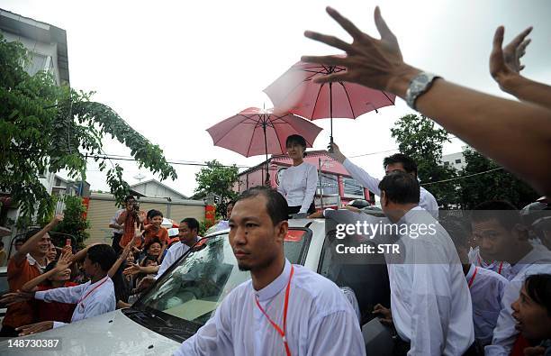 Myanmar opposition leader Aung San Suu Kyi waves to her supporters as she leaves a ceremony in honour of her late father, independence hero General...