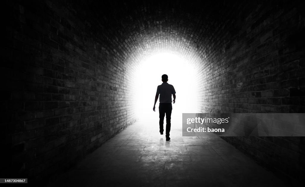 Joven caminando por un túnel oscuro