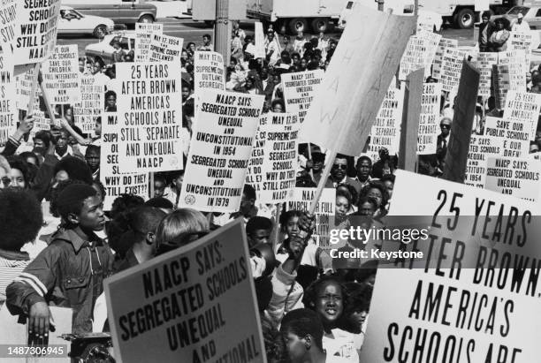 Black youths with signs that read "25 years after Brown, America's schools are still 'separate and unequal' NAACP", "NAACP says: Segregated schools...