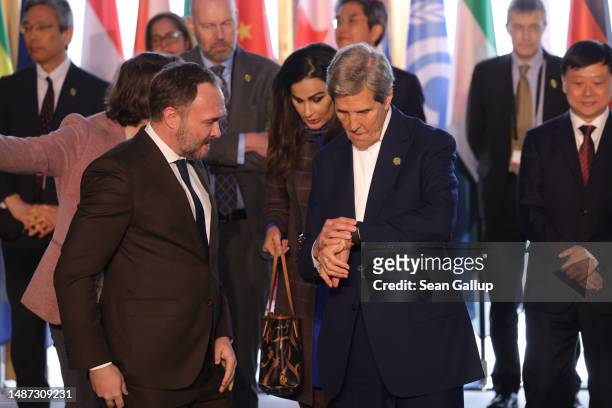 Special Presidential Envoy for Climate John Kerry looks at his watch as he chats with Danish Environment Minister Dan Jorgensen on the second and...