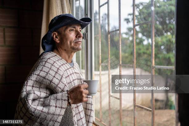 homme mûr contemplant de regarder par la fenêtre d’une maison de ferme - medellin photos et images de collection