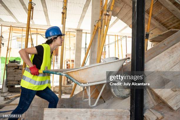 house construction, working woman pushes the wheelbarrow during the construction of a house - foreman stock pictures, royalty-free photos & images