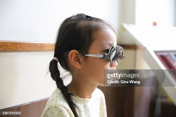 an asian girl doing a vision check in the clinic - monacle glasses stock pictures, royalty-free photos & images