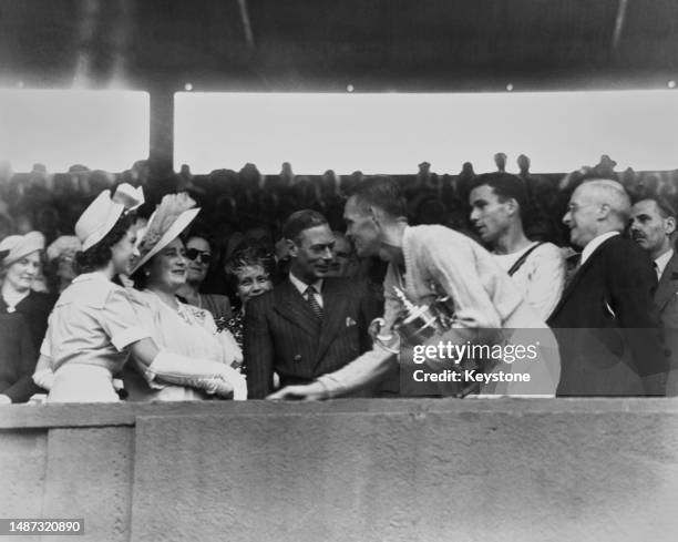 American tennis players Jack Kramer , holding winners trophy, and runner up, Tom Brown in the royal box being congratulated by Princess Margaret ,...