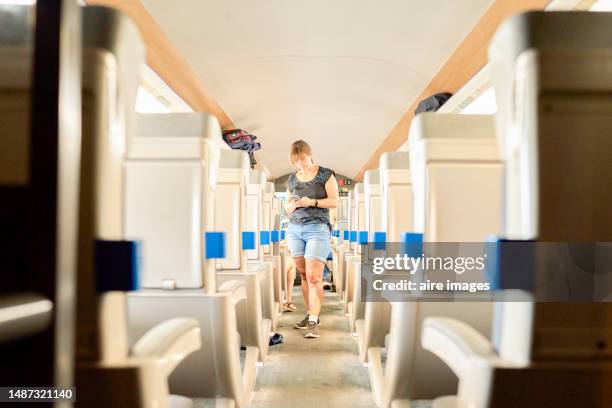 caucasian woman with long brown hair and casual clothes standing in the aisle of a vehicle. - french stock pictures, royalty-free photos & images