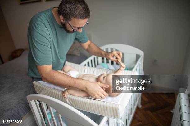 padre che cambia mestolo e gioca con il suo bambino - adult baby boy diaper change foto e immagini stock