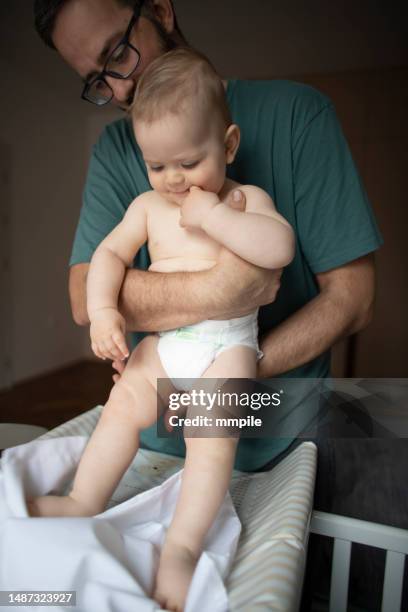father dressing and playing with his baby boy - adult baby boy diaper change stock pictures, royalty-free photos & images