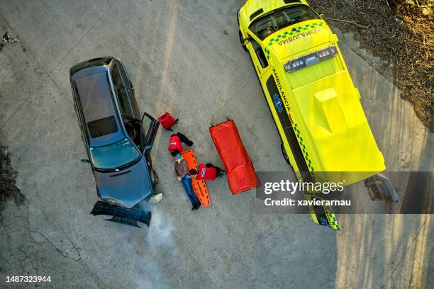 paramedics moving man onto spinal board at accident site - car crash top view stock pictures, royalty-free photos & images