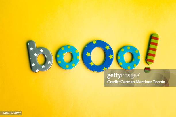 word 'booo!' with metallic letters on yellow background. - ugly wallpaper stock pictures, royalty-free photos & images