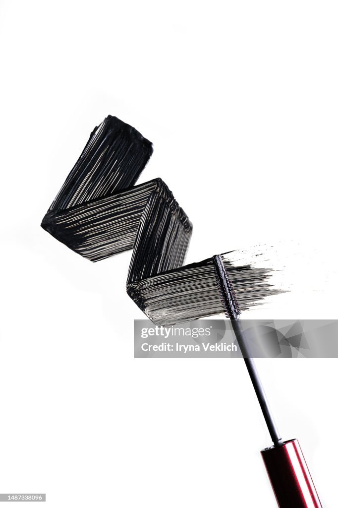 Black smear of black eye liner from a Mascara Brush on white background, isolated. Cosmetic make-up products for eyelashes.