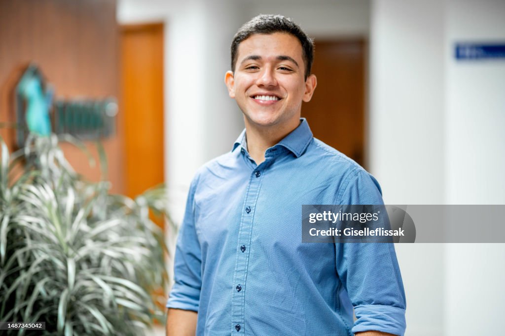 Smiling young businessman standing in the corridor of an office