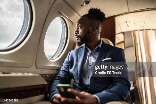 hombre de negocios adulto medio contemplando en un jet privado - real businessman isolated no smile fotografías e imágenes de stock