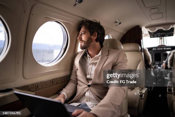 mid adult businessman contemplating on a private jet - billionaires stock pictures, royalty-free photos & images