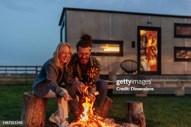 romantic couple at campfire. - log cabin stock pictures, royalty-free photos & images