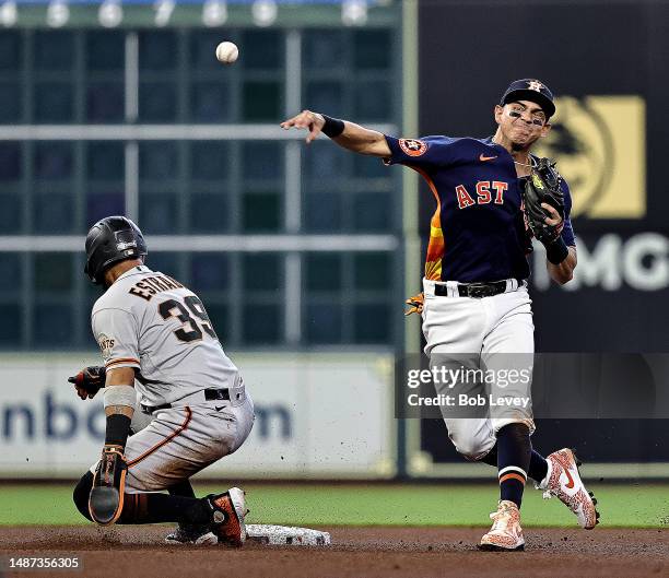 Mauricio Dubon of the Houston Astros throws to first base to complete a double play in the fourth inning as Thairo Estrada of the San Francisco...
