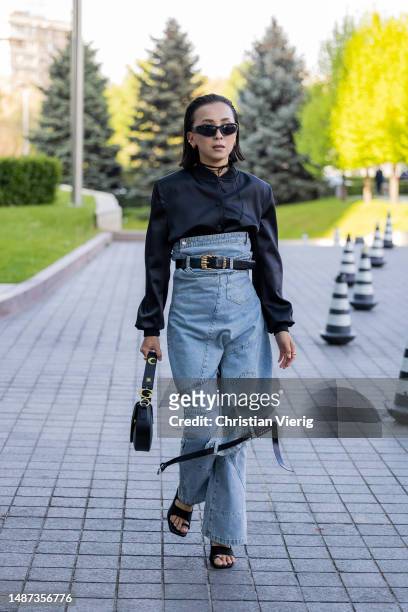 Guest is seen wearing high waisted light washed denim skirt, black blouse, bag at VISA Fashion Week Almaty Season VII on May 03, 2023 in Almaty,...