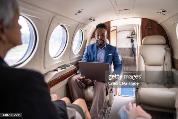 hombre de negocios adulto medio trabajando usando una computadora portátil en un avión privado - real businessman isolated no smile fotografías e imágenes de stock