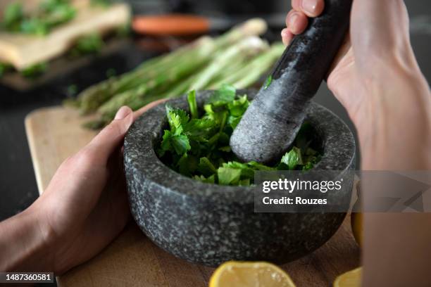 grinding herbs with a mortar and pestle - herb stockfoto's en -beelden