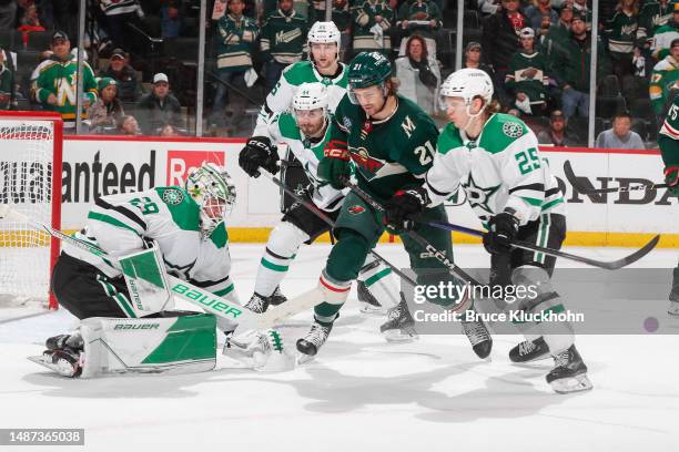 Jake Oettinger of the Dallas Stars makes a save in front of Joel Kiviranta and Brandon Duhaime of the Minnesota Wild in period three of Game Six of...