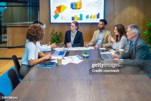 diverse group of people meeting and working at a board room table at a business presentation or seminar - round table discussion stock pictures, royalty-free photos & images