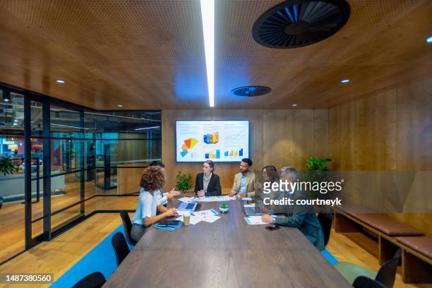 diverse group of people meeting and working at a board room table at a business presentation or seminar - round table imagens e fotografias de stock