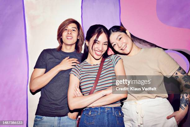 happy friends standing in front of wall - thai women stock pictures, royalty-free photos & images