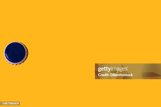blue bottle cap, on he left side, on a yellow background. concept for beer, drinks, alcohol, soft drinks, soft drinks, metal, industry and collectibles. - flaschenverschluss stock-fotos und bilder