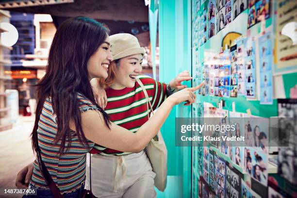smiling female friends pointing at photos - photo booth sign stock pictures, royalty-free photos & images