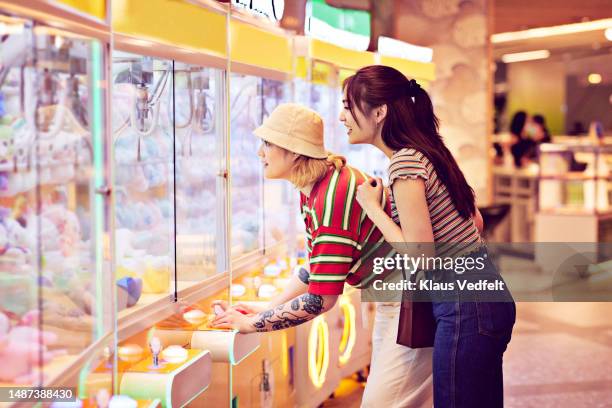 women playing grabbing game in arcade - máquina de apanhar brinquedos imagens e fotografias de stock